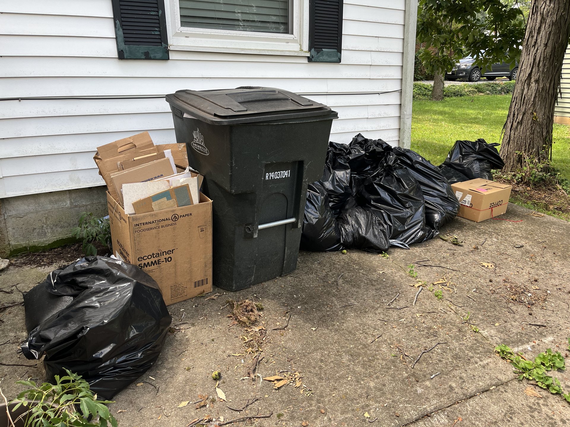 Trash bags, cardboard, and a Nashville bin staged for hauling