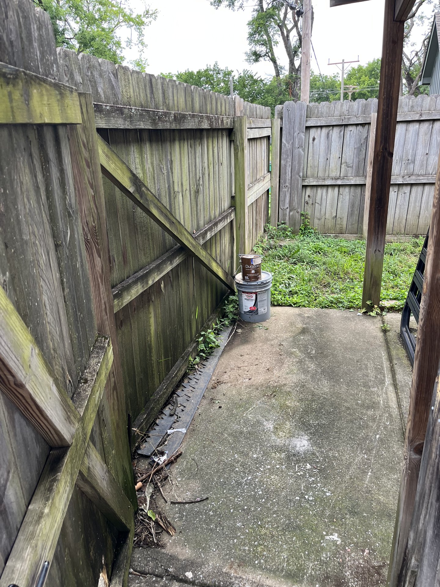 Paint cans and debris in a fenced side yard