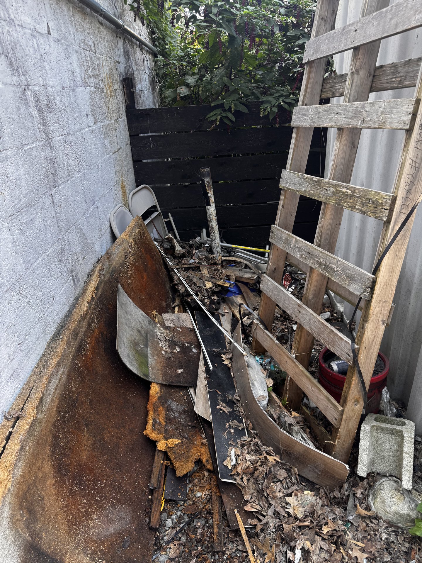 Metal, wood, and yard junk in a tight side yard